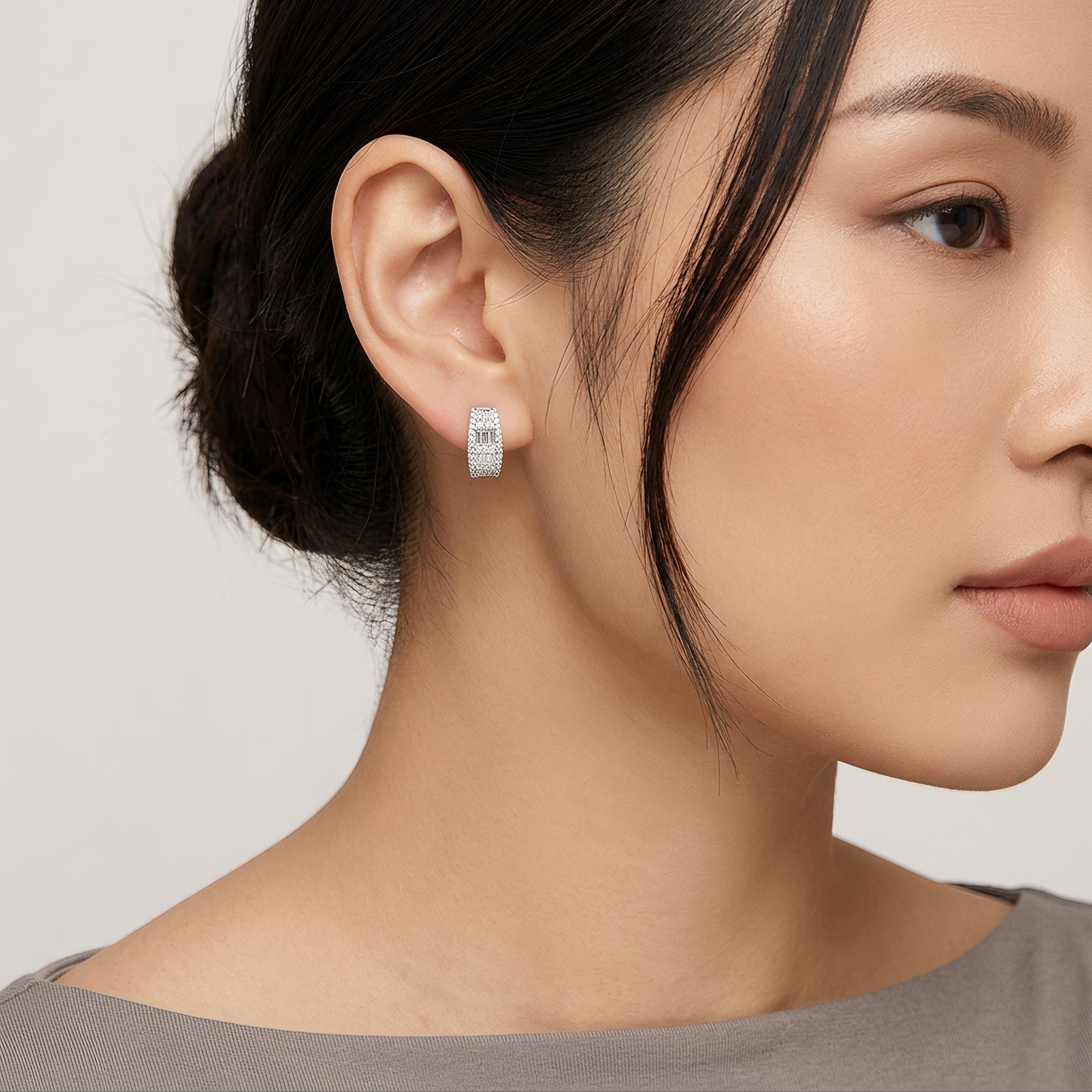 Model wearing an 18K white gold baguette and round diamond huggie hoop earring
