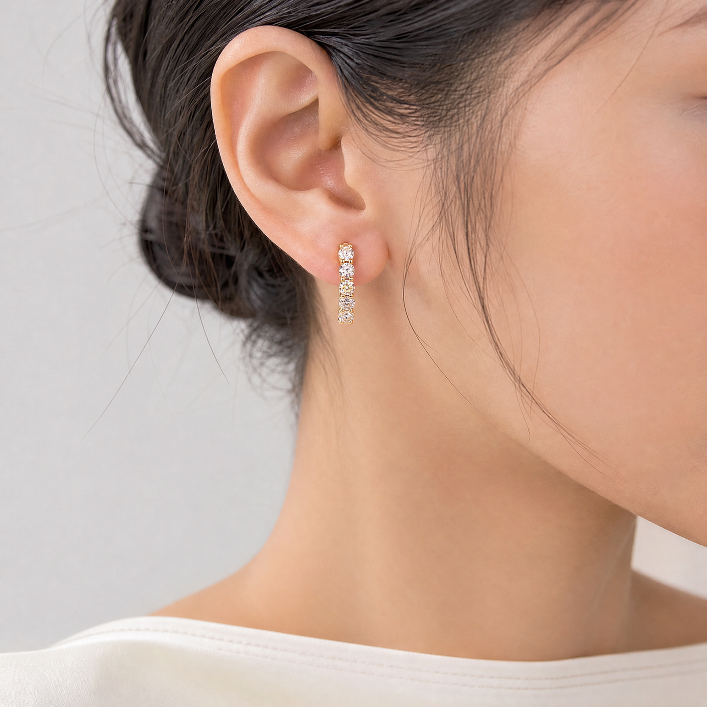 DEM1344AYW-12 model shot - round diamond shared-prong oval hoop earring worn on ear