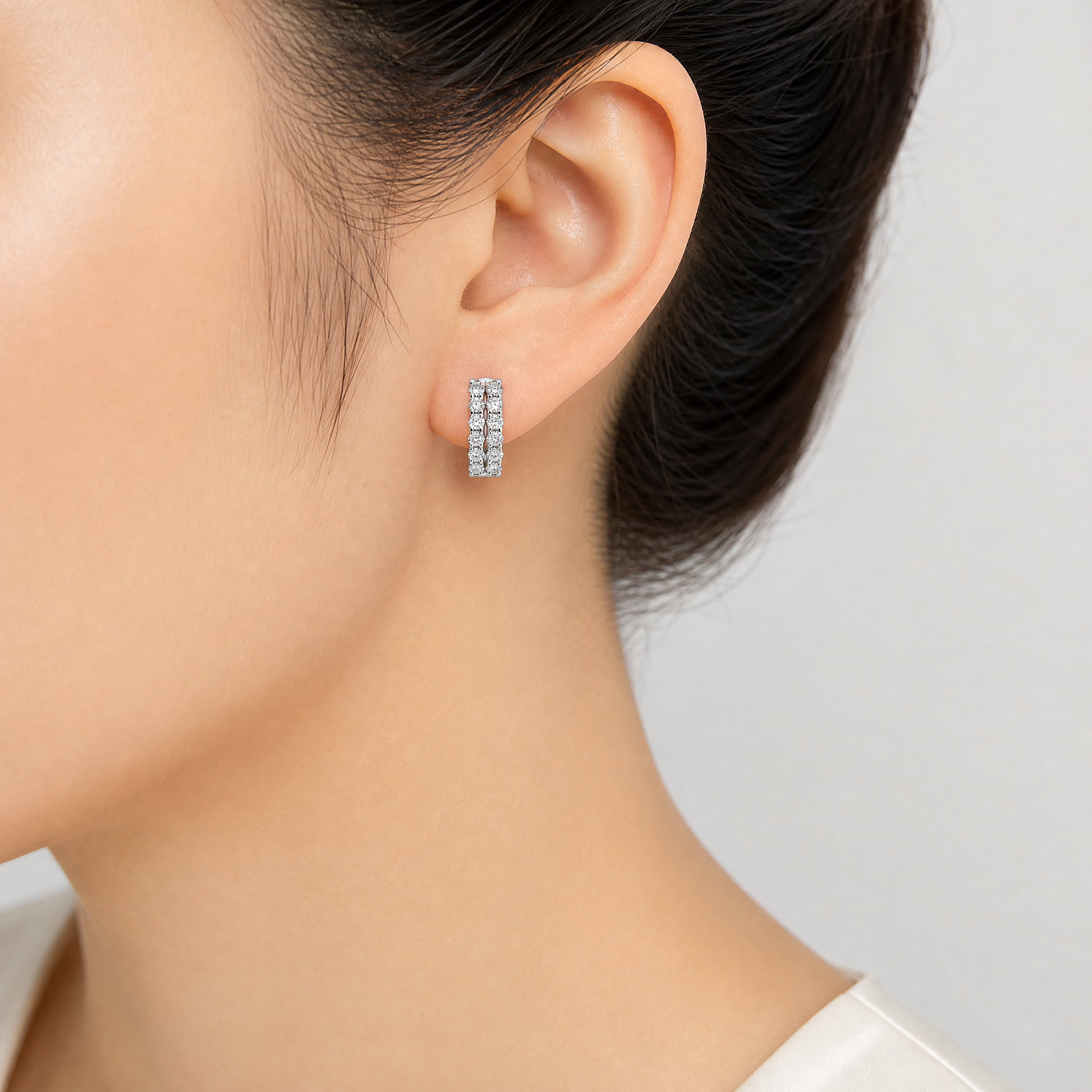 DESD0056W model shot - double-row round diamond white gold huggie hoop earring worn on ear