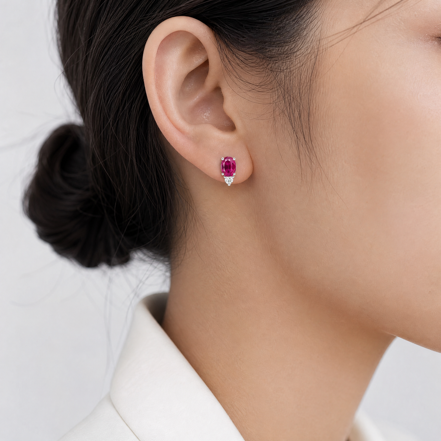 REPL0131DW-5 model shot - oval ruby stud earring with round diamond accent worn on ear