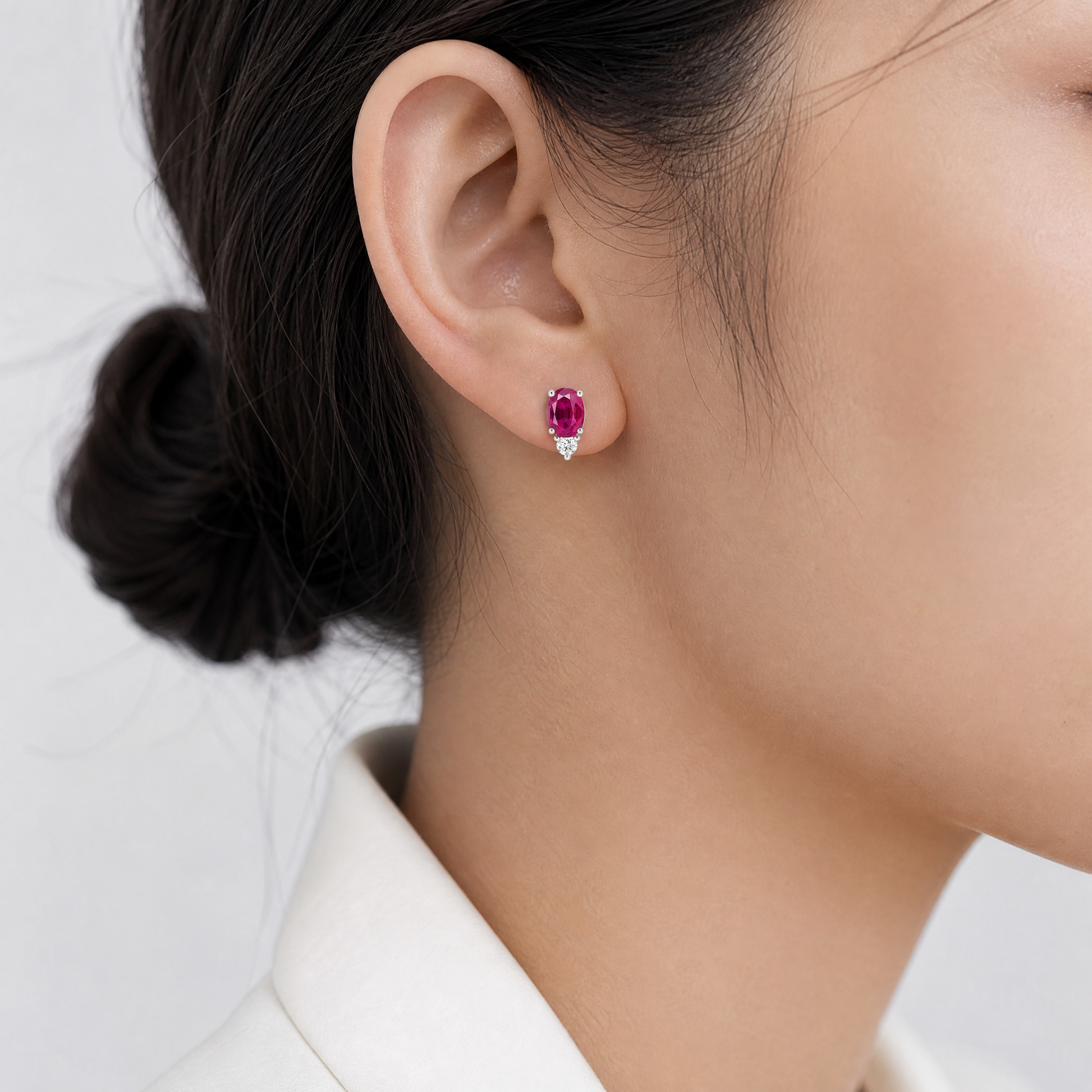REPL0131DW-5 model shot - oval ruby stud earring with round diamond accent worn on ear