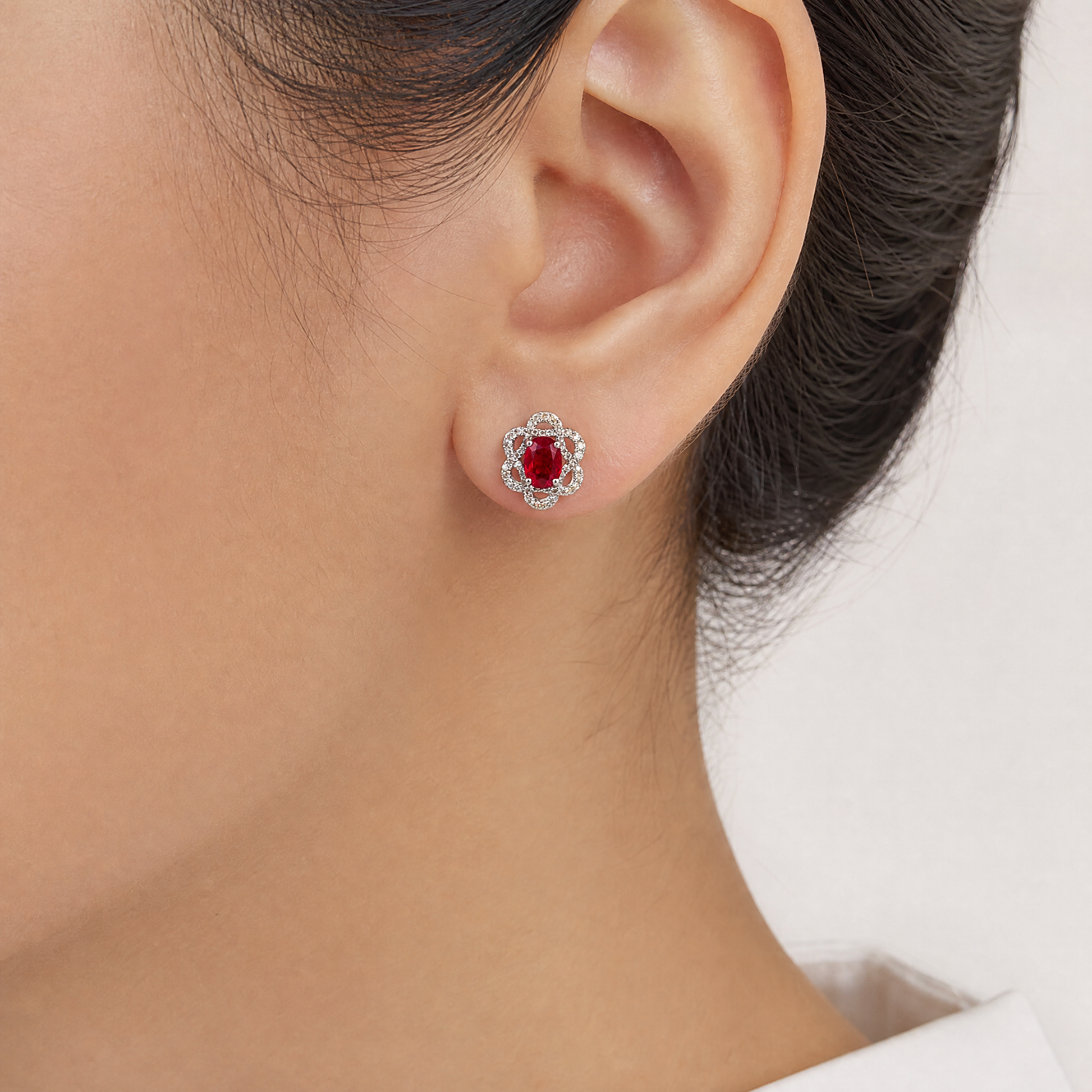 RERT0708W model shot - oval ruby and diamond openwork floral frame stud earring worn on ear