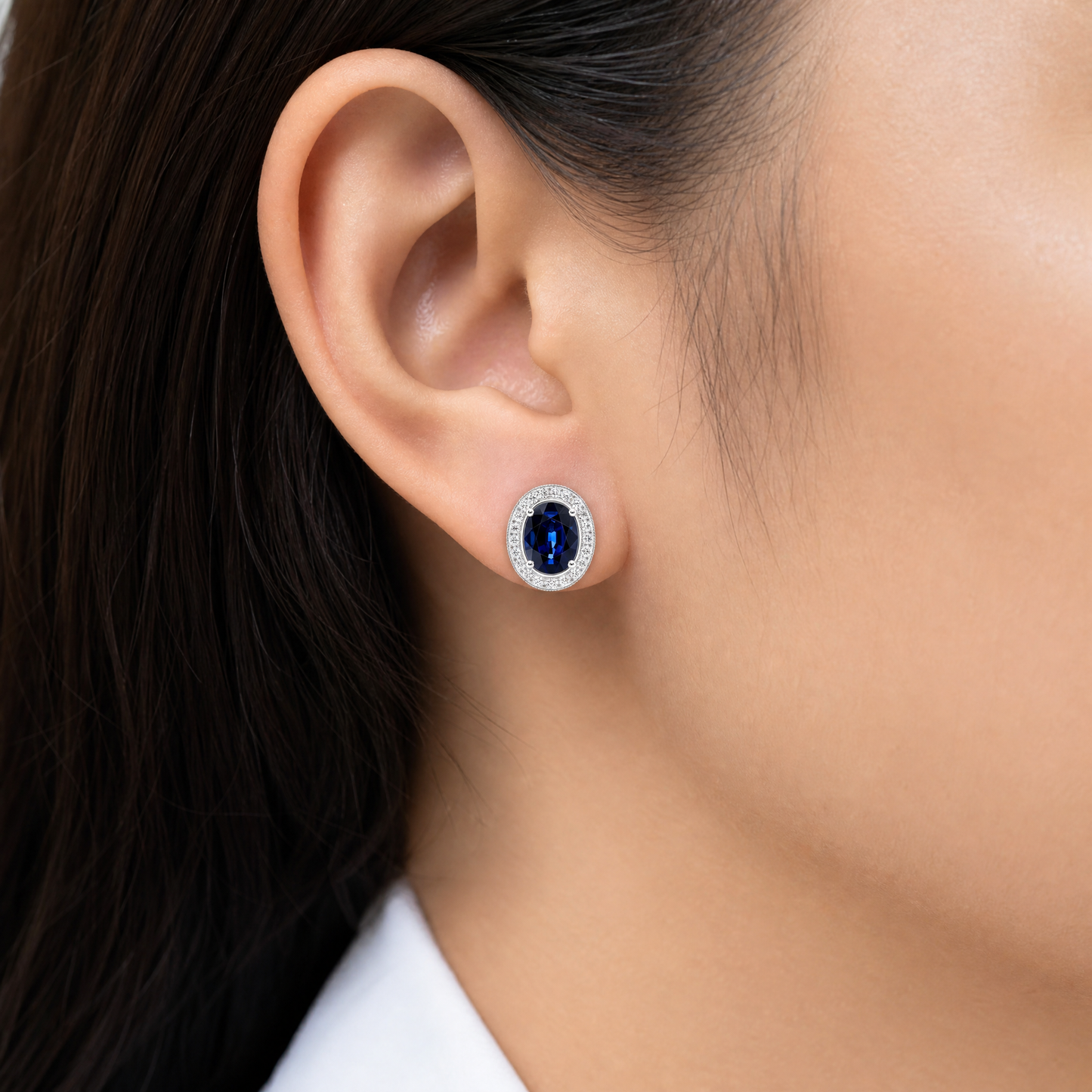 SERT0502W-OV model shot - oval blue sapphire milgrain halo stud earring worn on ear